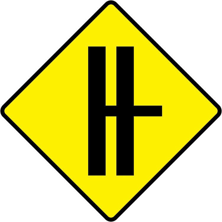 A triangular warning traffic sign in Ireland depicting side road on dual c'way - right (with cr break). Memorize for DTT.